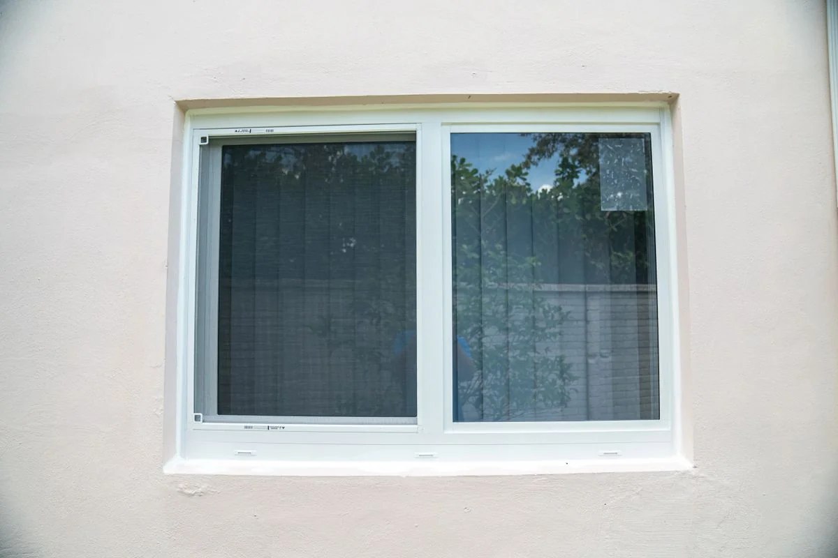 White frame impact slider installed in stucco wall